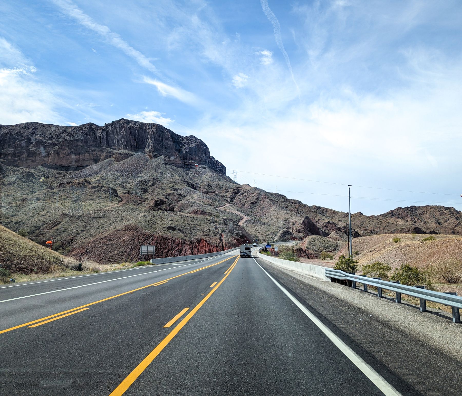 Straight desert highway leading toward rocky mountains beneath a clear sky